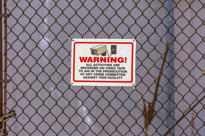 Close-up of warning sign on chainlink fence