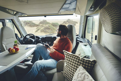 Mature man with digital tablet sitting in motor home on vacation