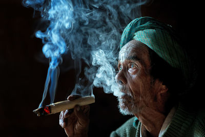 Close-up of man smoking against black background