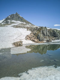 Nufenenpass with a mountain that is reflected in the water of the little lake