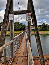 Information sign by bridge against sky