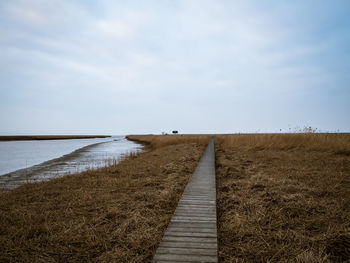 View of dirt road on field against sky