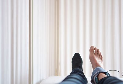 Low section of man relaxing on bed at home