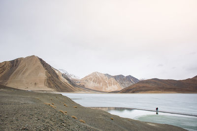 Scenic view of lake by mountains against sky