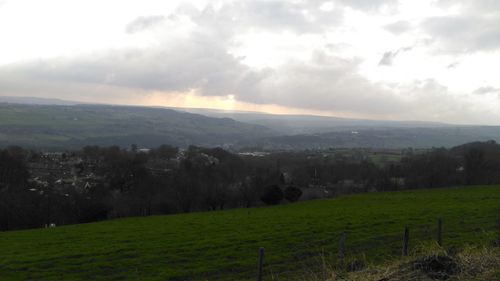 Scenic view of grassy field against cloudy sky