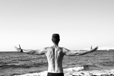 Shirtless man at beach against sky