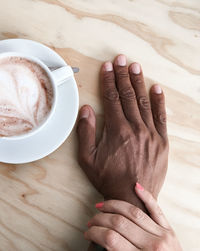 Close-up of hand holding coffee cup on table