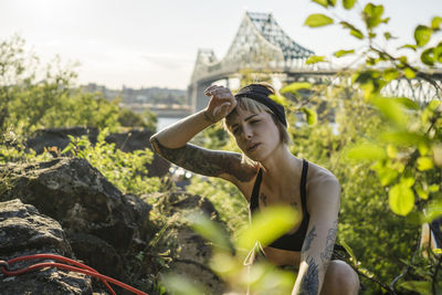 Tattooed girl rock climbing with friend reaching the top