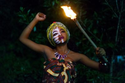 Portrait of young woman standing against blurred background