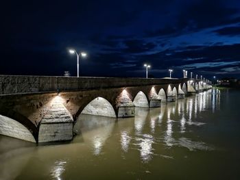Bridge over river against sky at night