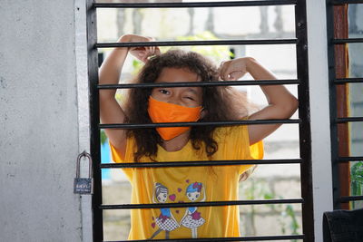 Portrait of young woman looking through window