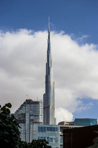 Low angle view of buildings in city against cloudy sky