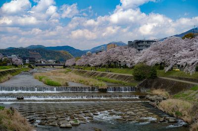 Scenic view of river by buildings against sky