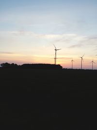 Silhouette windmill on landscape against sky at sunset