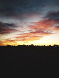 Silhouette landscape against dramatic sky during sunset