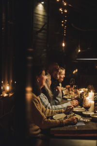 Male and female senior friends enjoying candlelight dinner together during party at night