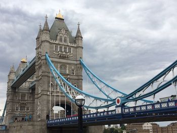 Low angle view of suspension bridge against cloudy sky