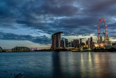 View of illuminated cityscape against cloudy sky