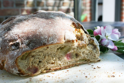 Close-up of bread by flowers on cutting board at table