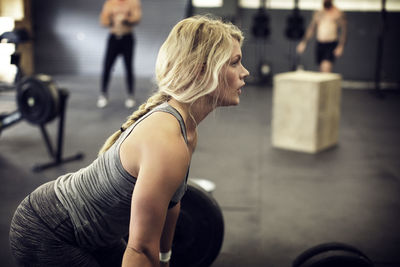 Side view of determined female athlete exercising in gym