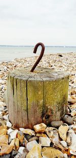 Close-up of wooden post on beach against sky