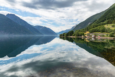 Scenic view of mountains reflecting on calm lake against cloudy sky