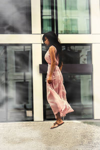 Side view of woman levitating against building