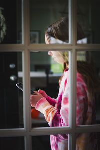 Rear view of woman standing by window