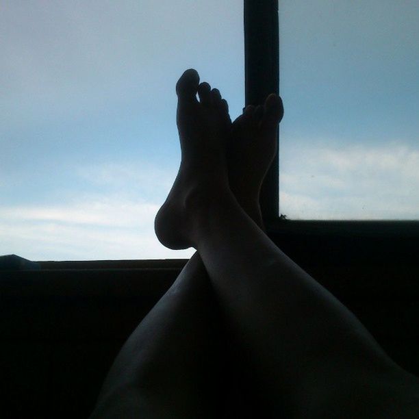 person, part of, indoors, sky, personal perspective, silhouette, relaxation, low section, lifestyles, cropped, barefoot, human finger, sunlight, window, unrecognizable person