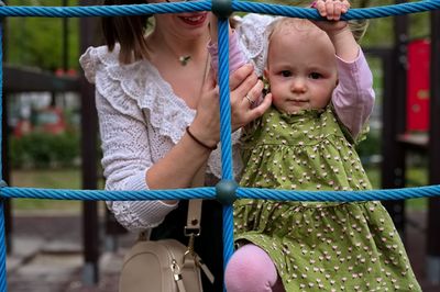 Mother holding her little baby girl on playground ladder
