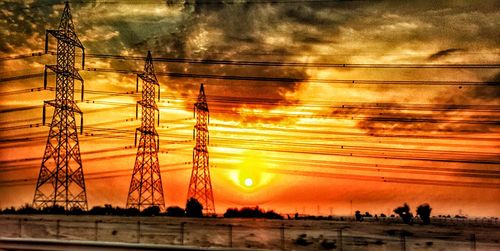 Silhouette of electricity pylon against sky during sunset