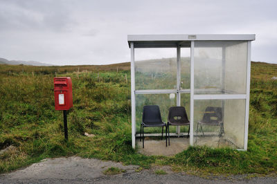 View of old telephone booth on field against sky