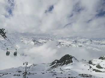 Scenic view of snow covered mountains against cloudy sky