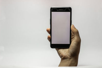 Close-up of hand holding smart phone over white background