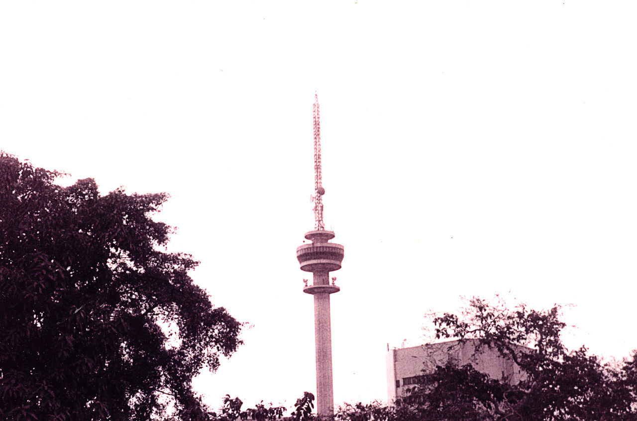 LOW ANGLE VIEW OF COMMUNICATIONS TOWER IN CITY AGAINST SKY