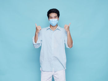 Portrait of young man standing against blue background