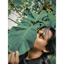 Close-up portrait of young woman with leaves