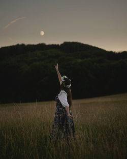 Happy woman looking at the moon on the field wearing dress and flowers