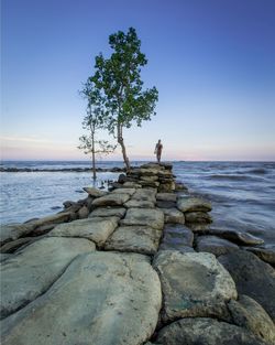 Scenic view of rocks by sea against sky