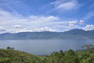 Scenic view of lake by mountains against sky