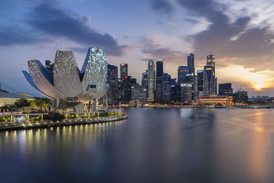 View of city at waterfront against cloudy sky