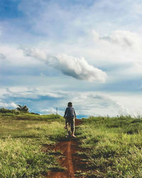 Rear view of man on field against sky