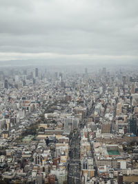 High angle view of city buildings against cloudy sky