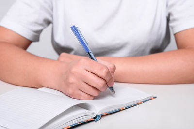 Midsection of woman reading book on table