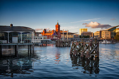 Pier over river by buildings against sky