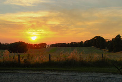 Scenic view of agricultural field against dramatic sky during sunset