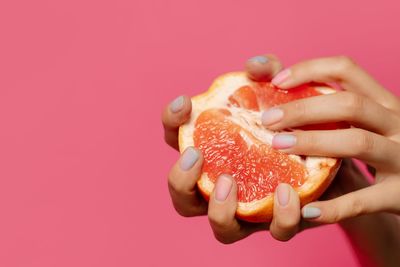 Close-up of woman holding strawberry over white background