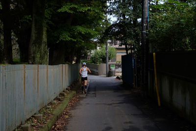 Rear view of man walking on footpath amidst trees