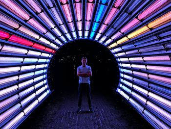 Man standing in colorful illuminated tunnel at night