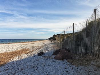 Fence on beach against sky